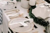 a chic and bright NYE wedding tablescape with a greenery runner, white candles, shiny ornaments and striped napkins