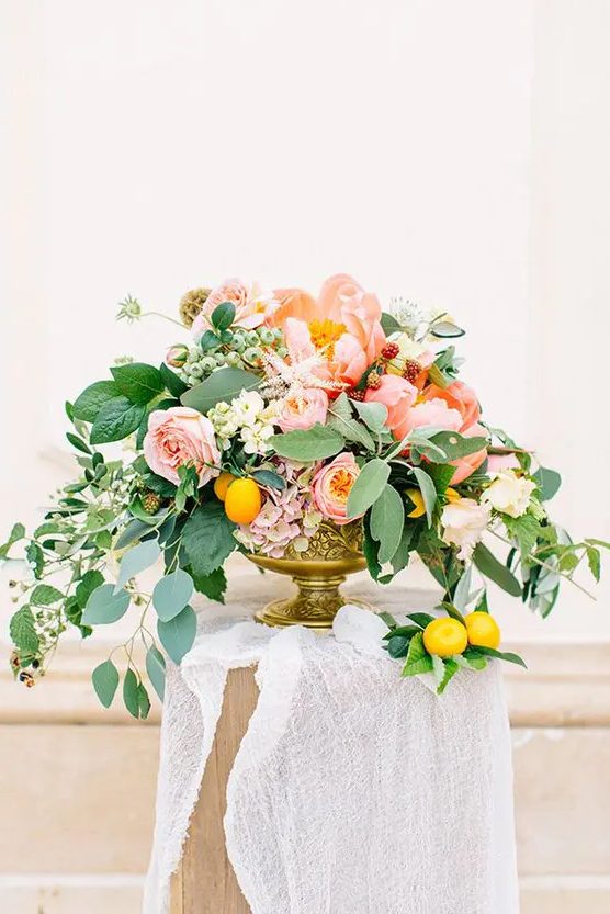 a chic and colorful peony centerpiece with pink and white blooms, cascading greenery and lemons