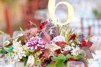a colorful wedding centerpiece of a crate with very bright blooms and greenery plus a table number