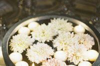 a concrete bowl with floating candles and blush blooms is a lovely idea for a tropical wedding
