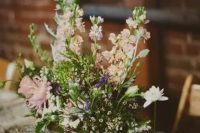 a cozy barn wedding centerpiece of a wooden box and some neutral and pink flowers plus greenery
