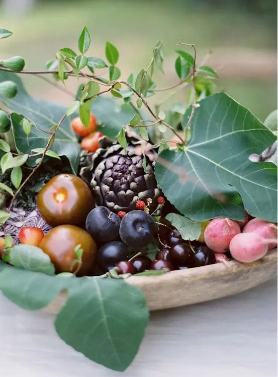 a cute fall wedding centerpiece done of veggies, fruits and some foliage for a rustic or garden wedding
