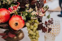 a decadent wedding centerpiece of a bowl with fruit, bold foliage and some wildflowers is amazing for the fall