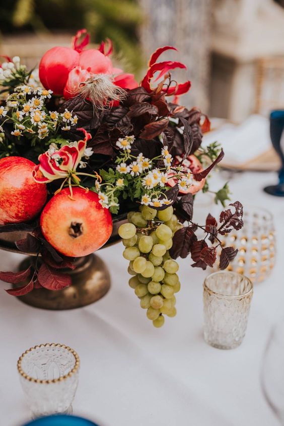 a decadent wedding centerpiece of a bowl with fruit, bold foliage and some wildflowers is amazing for the fall