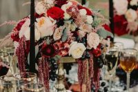 a decadent wedding centerpiece of a gilded bowl, blooms in blush and red and grapes for a luxurious feel