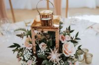 a delicate rustic wedding centerpiece of a tree slice, a lantern with blush blooms and greenery is amazing