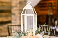 a delicate wedding centerpiece of greenery, blush blooms, a candle lantern is a cool and catchy idea for a rustic wedding