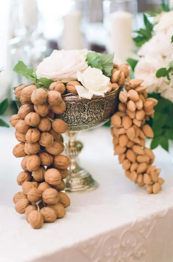 a fantastic wedding centerpiece of a vintage silver bowl, with lots of nuts and white blooms and greenery on top