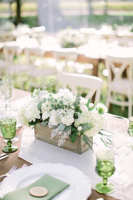 a fresh white wedding centerpiece of a wooden box with white flowers and some greenery is a cool idea for spring or summer