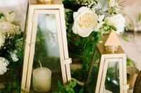 a lovely wedding centerpiece of greenery, neutral blooms and elegant metallic candle lanterns for a refined and romantic wedding