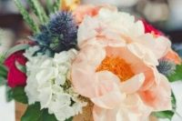 a pretty spring wedding centerpiece of a wooden box with pastel, white and bold blooms and thistles