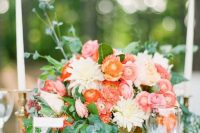 a refined summer wedding centerpiece of a gold urn, red and pink and white flowers, foliage is chic