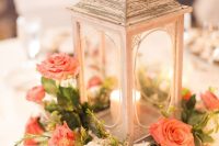 a refined wedding centerpiece of a lantern surrounded with coral and white blooms and greenery