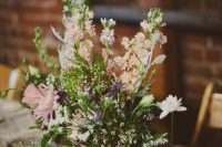 a relaxed wedding centerpiece of a wooden box, blush, white and purple blooms and greenery for spring or summer