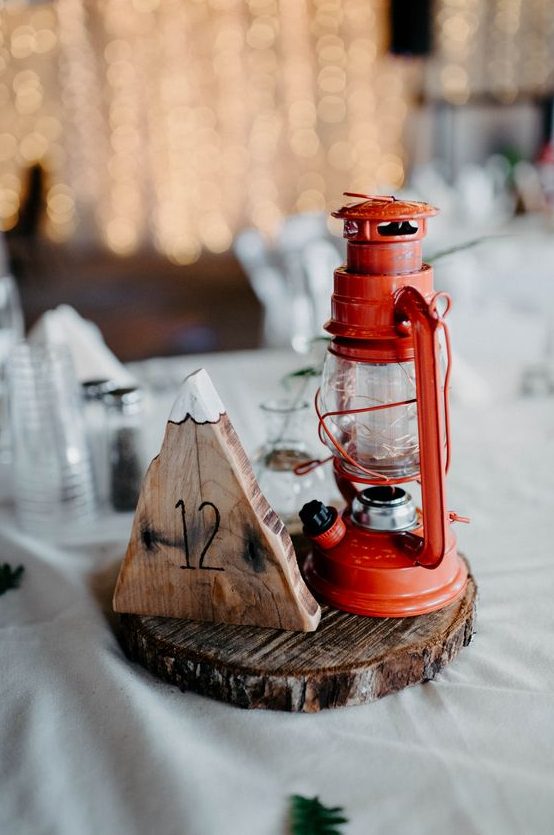 a rustic and camp winter wedding centerpiece of a wood slice, a mountain of wood and a lantern is great