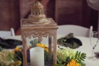 a rustic vintage wedding centerpiece with a candle lantern surrounded with green hydrangeas, sunflowers, greenery is a lovely idea