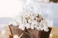 a rustic wedding centerpiece of a rich-stained wooden box filled with cotton, candles and antlers is a gorgeous idea to go for