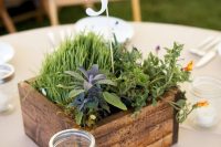 a rustic wedding centerpiece of a stained box with greenery, grass and a table number is easy and cool