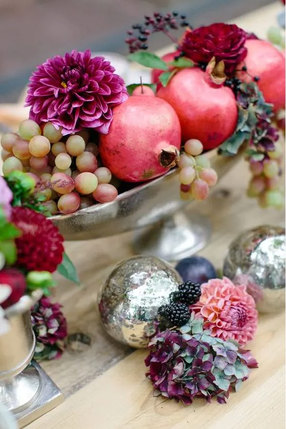 a silver bowl with grapes, pomegranates, fuchsia and deep red blooms and berries is a beautiful fall wedding centerpiece