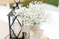 a stylish rustic centerpiece with a candle lantern and a mason jar with baby’s breath can be easil DIYed