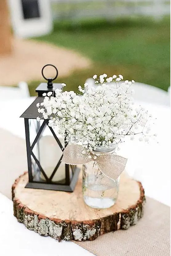 a stylish rustic centerpiece with a candle lantern and a mason jar with baby's breath can be easil DIYed