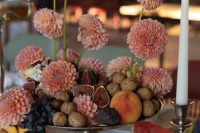 a unique wedding centerpiece of a bowl with fruit, nuts and coral blooms is adorable for summer or fall