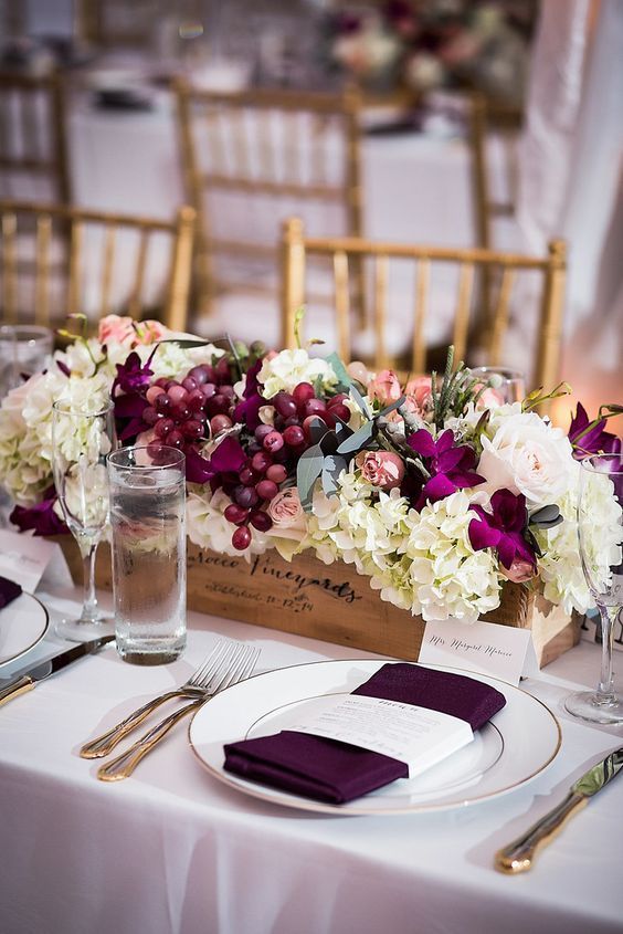 a vineyard wedding centerpiece of a wooden box of white hydrangeas and grapes is contrasting and adorable