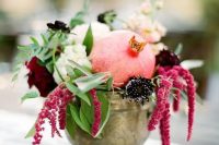 a vintage bowl with white, burgundy and deep purple blooms, greenery and a pomegranate is a lovely fall wedding centerpiece you can compose yourself