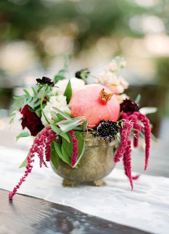 a vintage bowl with white, burgundy and deep purple blooms, greenery and a pomegranate is a lovely fall wedding centerpiece you can compose yourself
