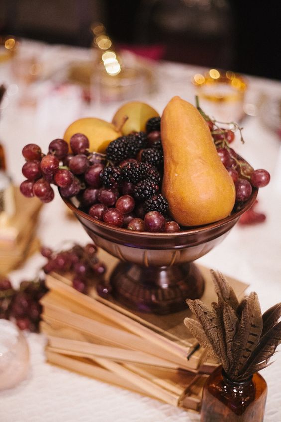 a vintage wedding centerpiece of a book stack and a bowl with fresh fruit will be great for a fall vintage wedding
