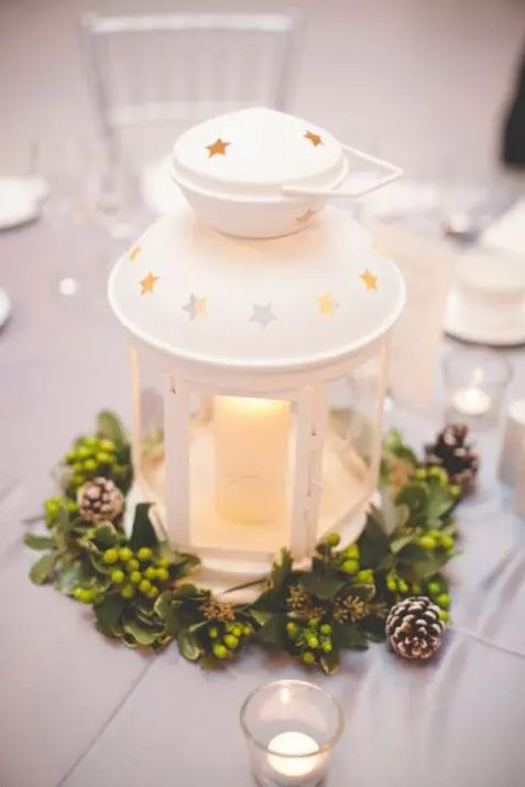 a white IKEA lantern centerpiece with a greenery wreath with berries and pinecones is ideal for Christmas
