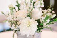 a white wedding centerpiece of a whitewashed box with white blooms and greenery is a catchy solution