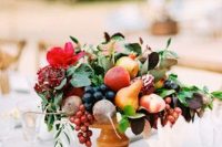 a wooden bowl with lots of fruit, berries, leaves and bright blooms is a lovely summer or fall wedding centerpiece