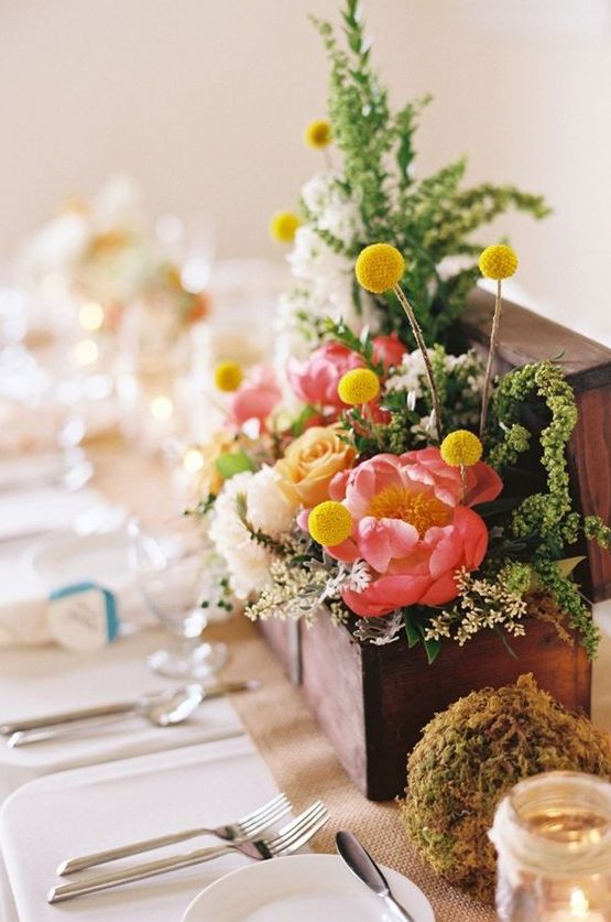 a wooden box with greenery, coral and peachy and white blooms, billy balls and a moss ball is a cool idea to rock