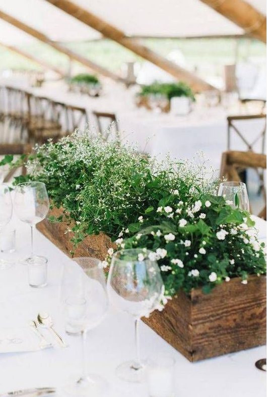 an easy spring wedding centerpiece of a wooden box with various greenery and small white blooms for a modern rustic wedding