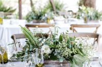 an organic wedding centerpiece of a wooden box with greenery and white blooms plus seed pods is cool