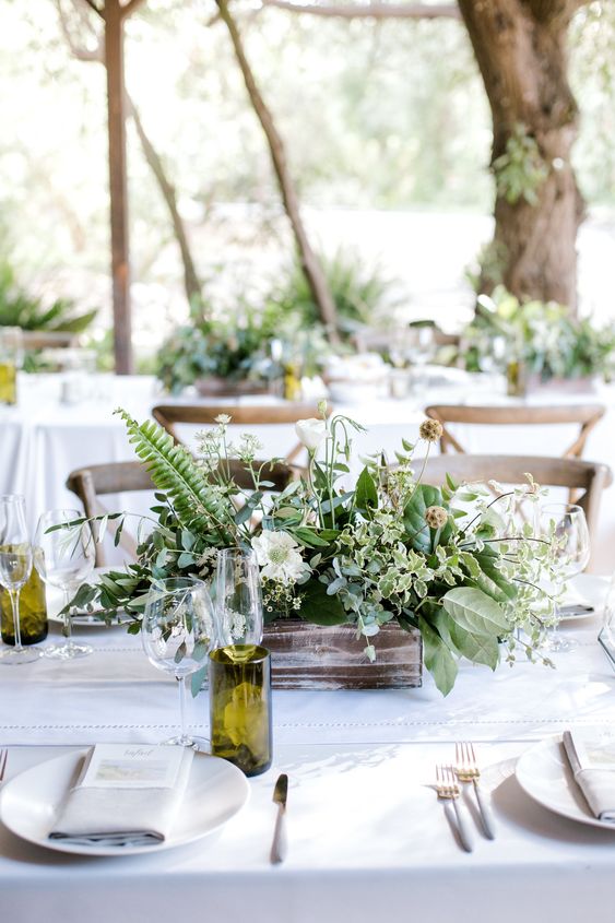 an organic wedding centerpiece of a wooden box with greenery and white blooms plus seed pods is cool