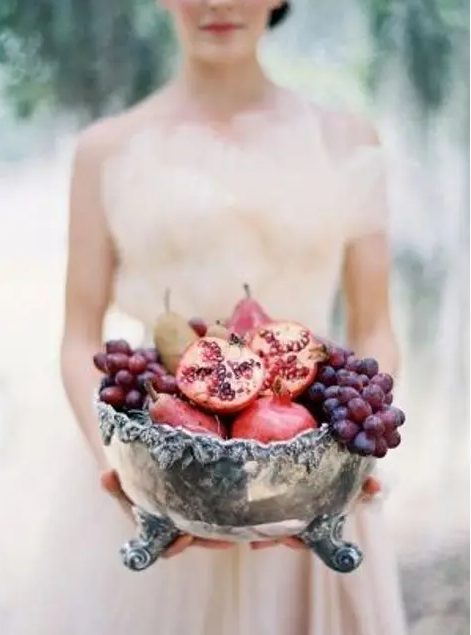 An oversized silver bowl with pomegranates and grapes is a beautiful and delicious looking idea for a fall wedding with a decadent feel