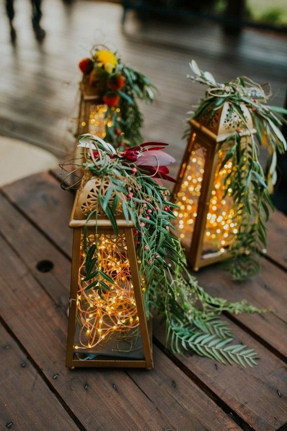 lanterns with lights, bold blooms and greenery on top are amazing for stylign your wedding table