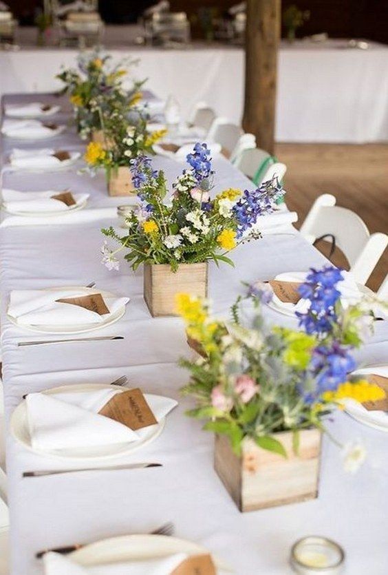 small colorful wedding centerpieces of wooden boxes, greenery, blue and yellow blooms are amazing