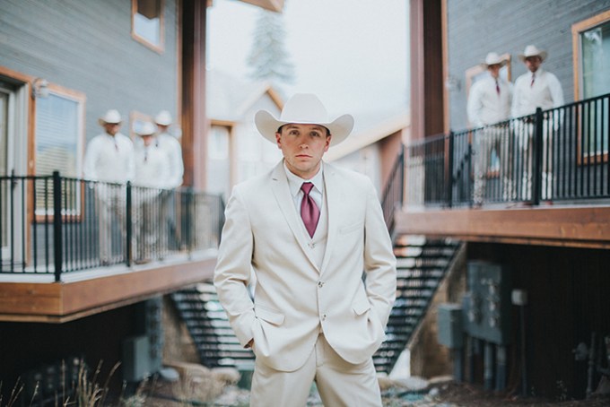 The groom was wearing a neutral suit, a burungdy tie and a cowboy hat