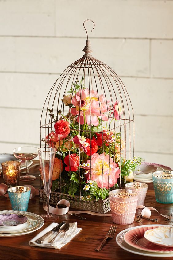 a vintage cage with lush red and pink blooms and greenery for a colorful wedding