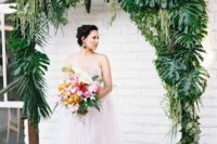 05 a wedding arch decorated with tropical leaves and hanging greenery and foliage