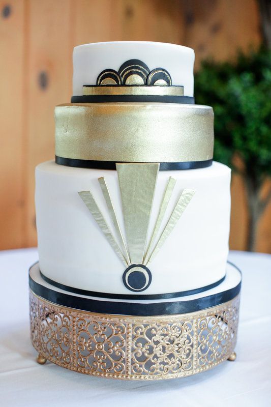 a black, white and gold wedding cake with scallops and geo decor