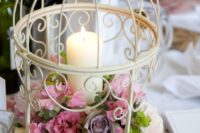 06 a white birdcage with lush pink blooms and a candle but be careful not to burn the flowers