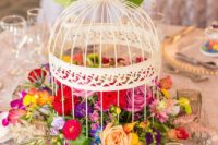 07 a decorative white cage filled with lush and bold florals for a summer garden wedding