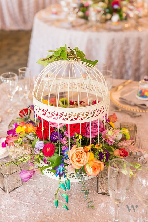 a decorative white cage filled with lush and bold florals for a summer garden wedding