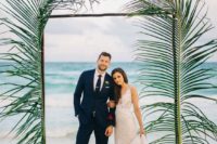07 a tropical wedding arch decorated with large leaves is an easy and chic idea