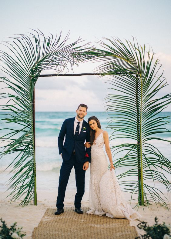 a tropical wedding arch decorated with large leaves is an easy and chic idea