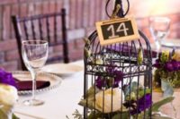 08 a dark birdcage with purple and white flowers and moss for a bold wedding, a chalkboard table number